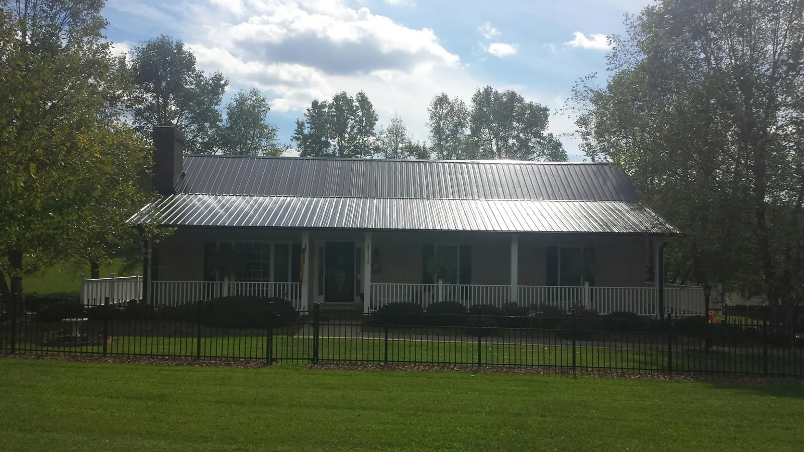 Gray metal roof on a brick ranch with a full width front porch — Gutter Guard Installation work by our crew in Girard